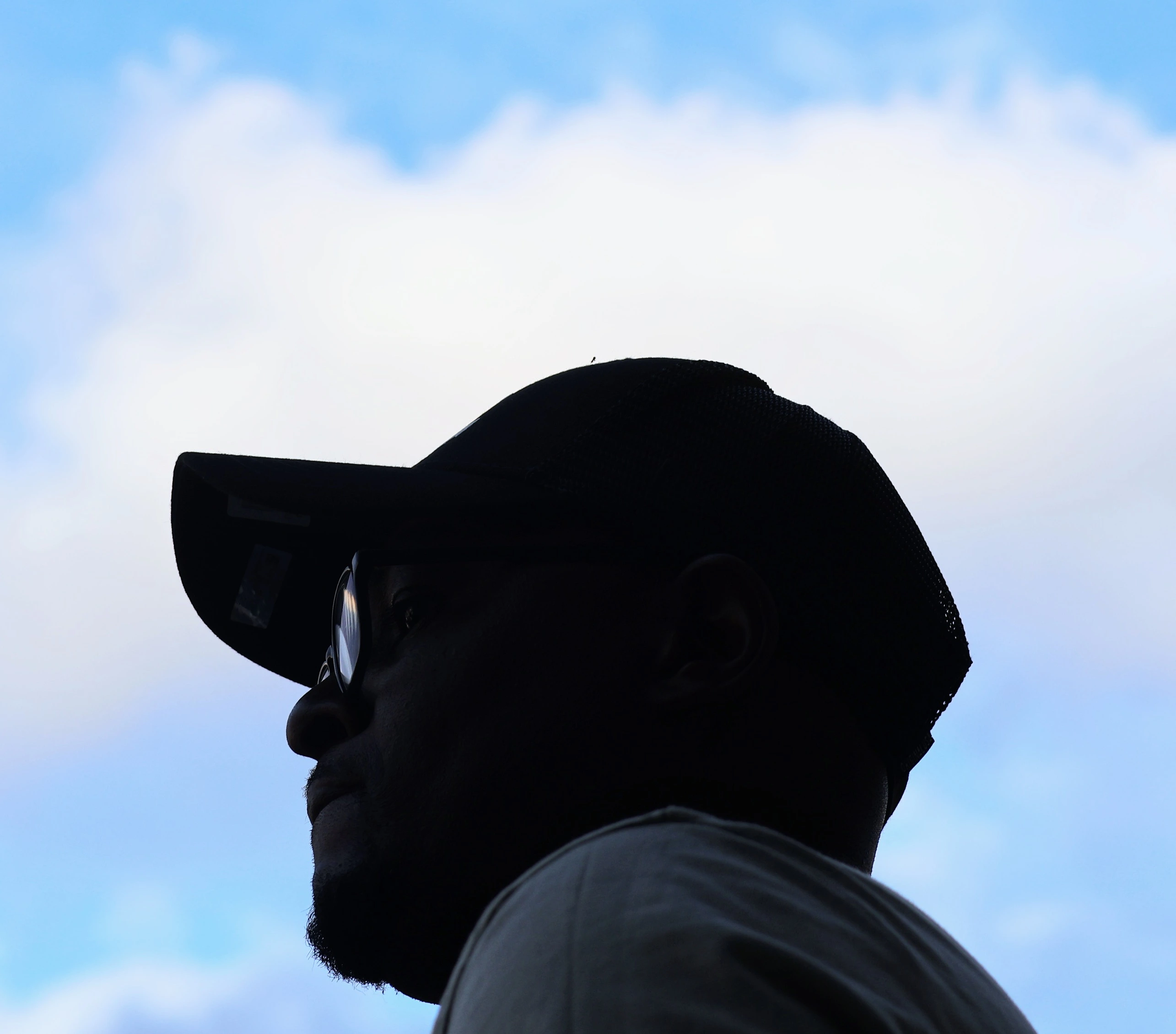 Silhouette of man in baseball cap against open blue sky