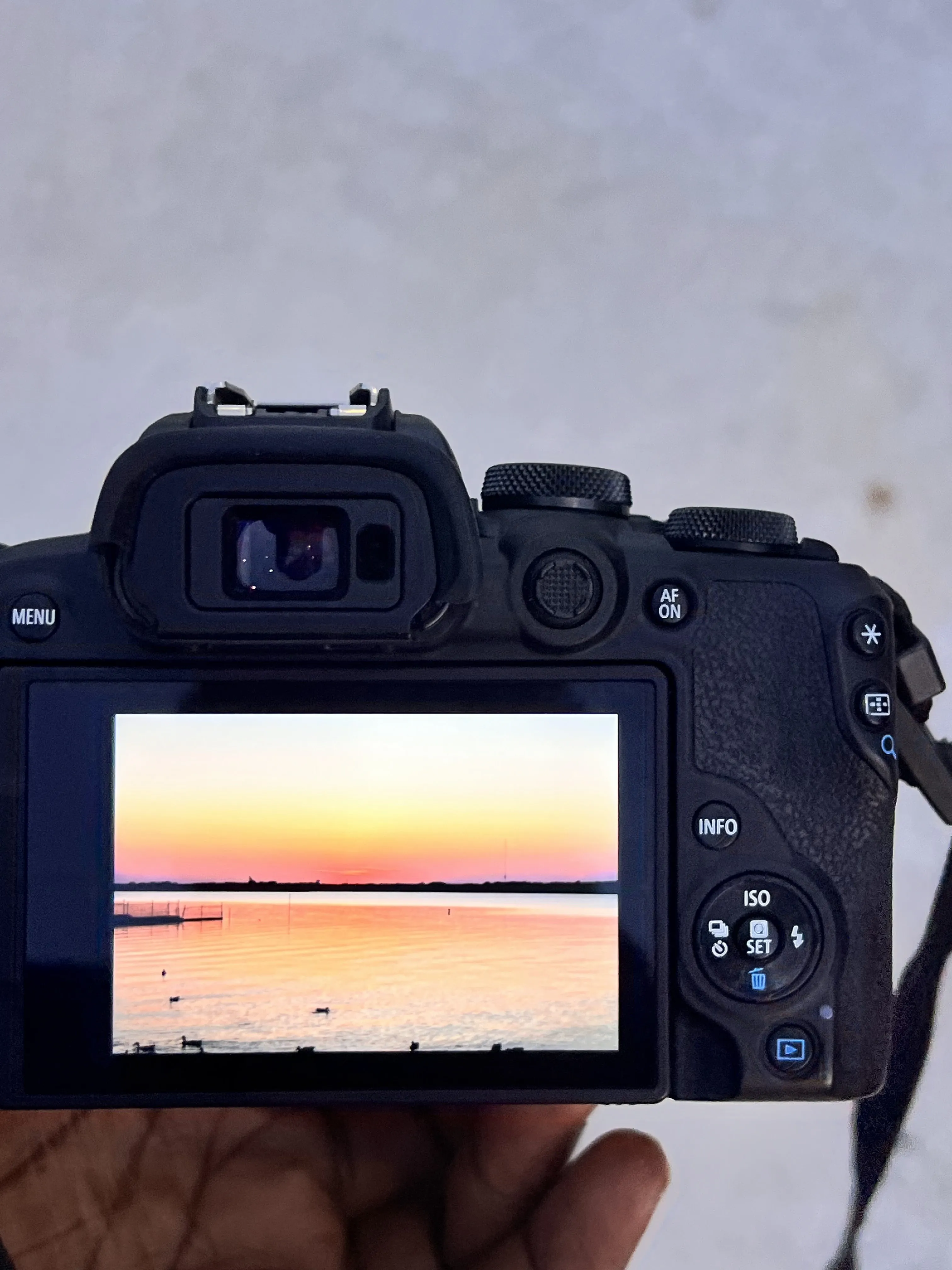 Canon camera LCD showing a glowing sunset over water