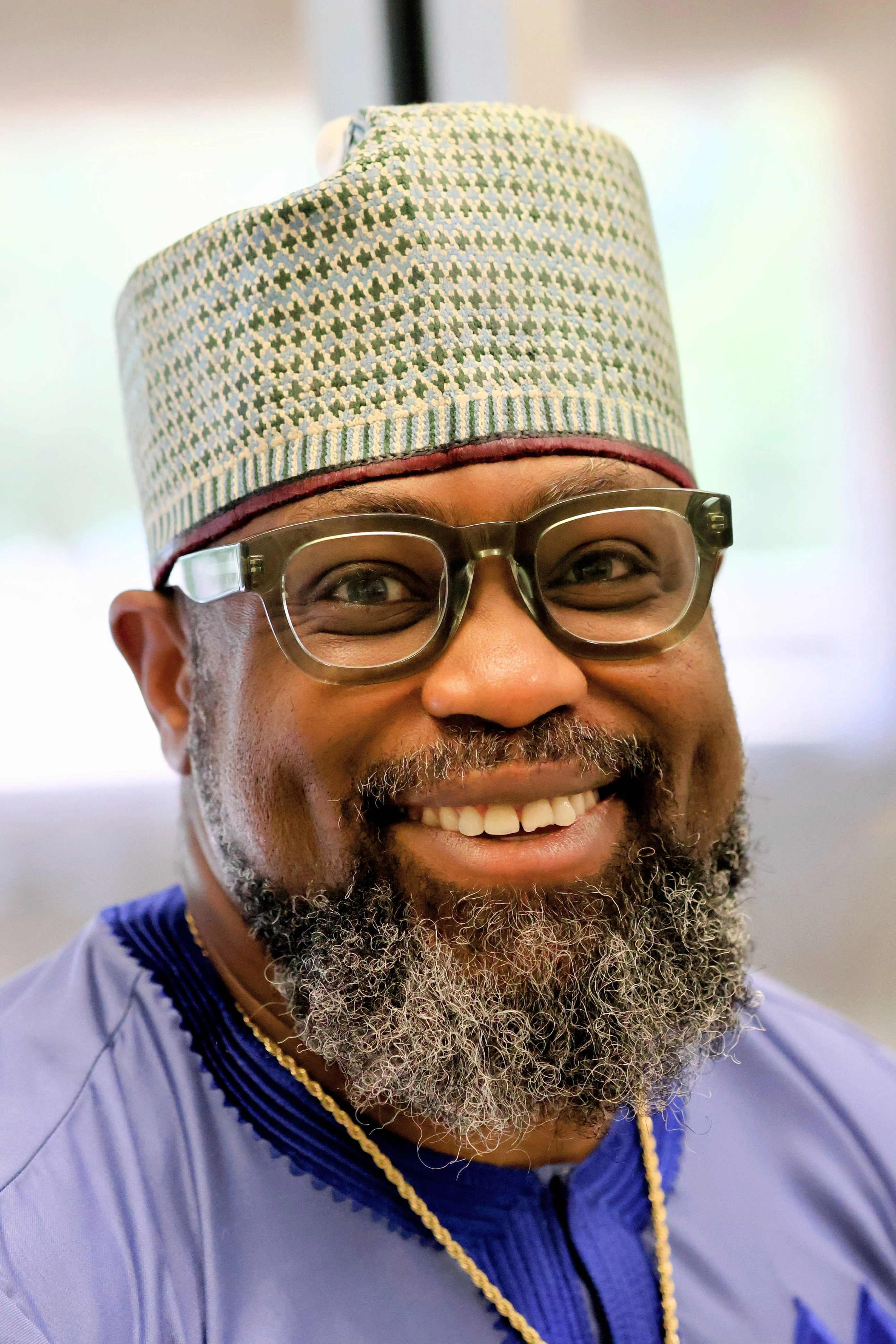 Portrait - man in traditional kufi and agbada, warm smile