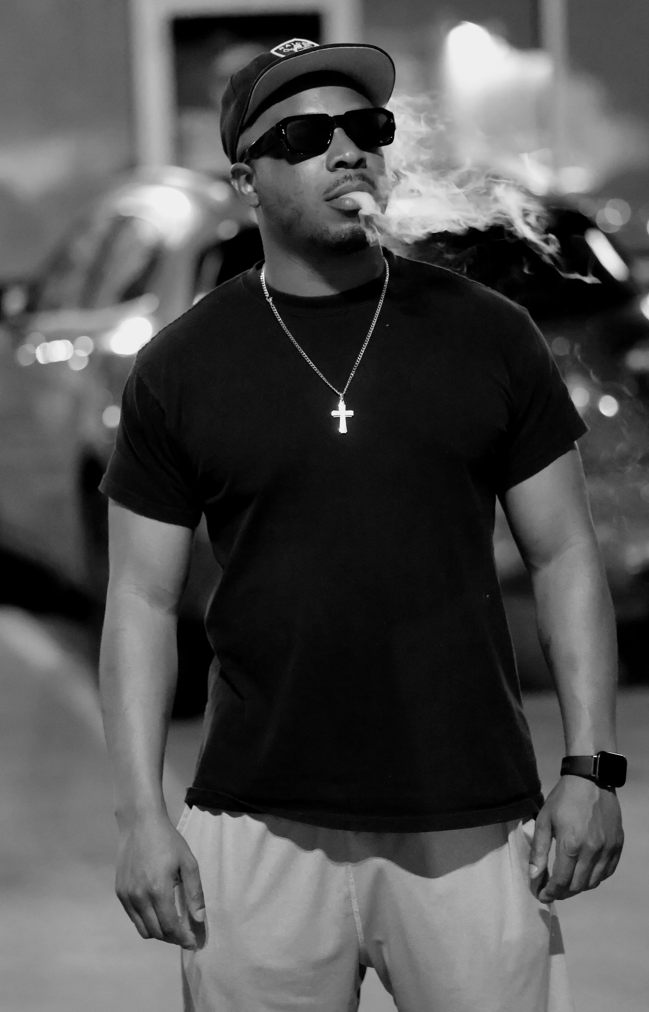Black and white portrait - man in snapback cap and sunglasses exhaling smoke