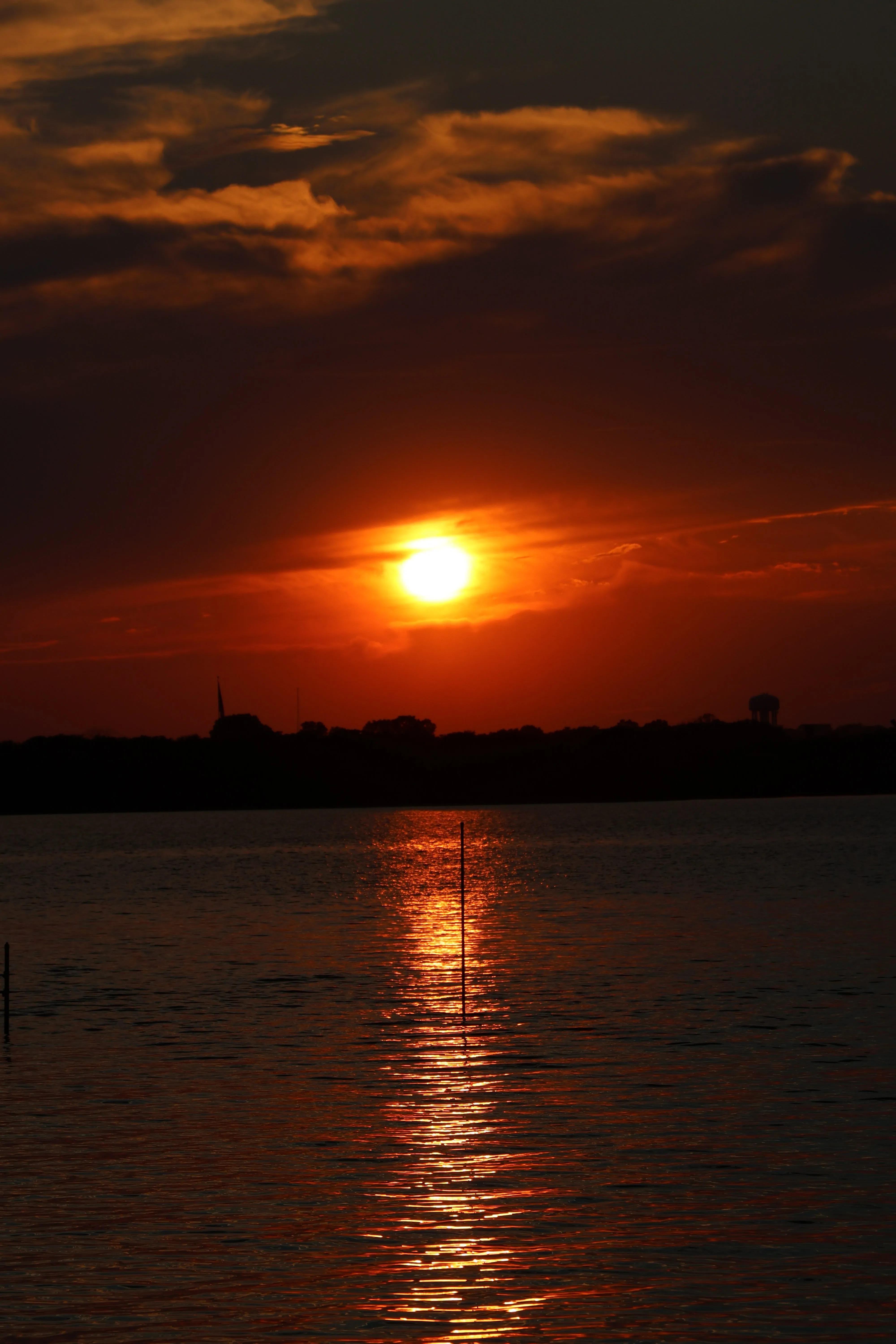Fiery sunset over water with city silhouette