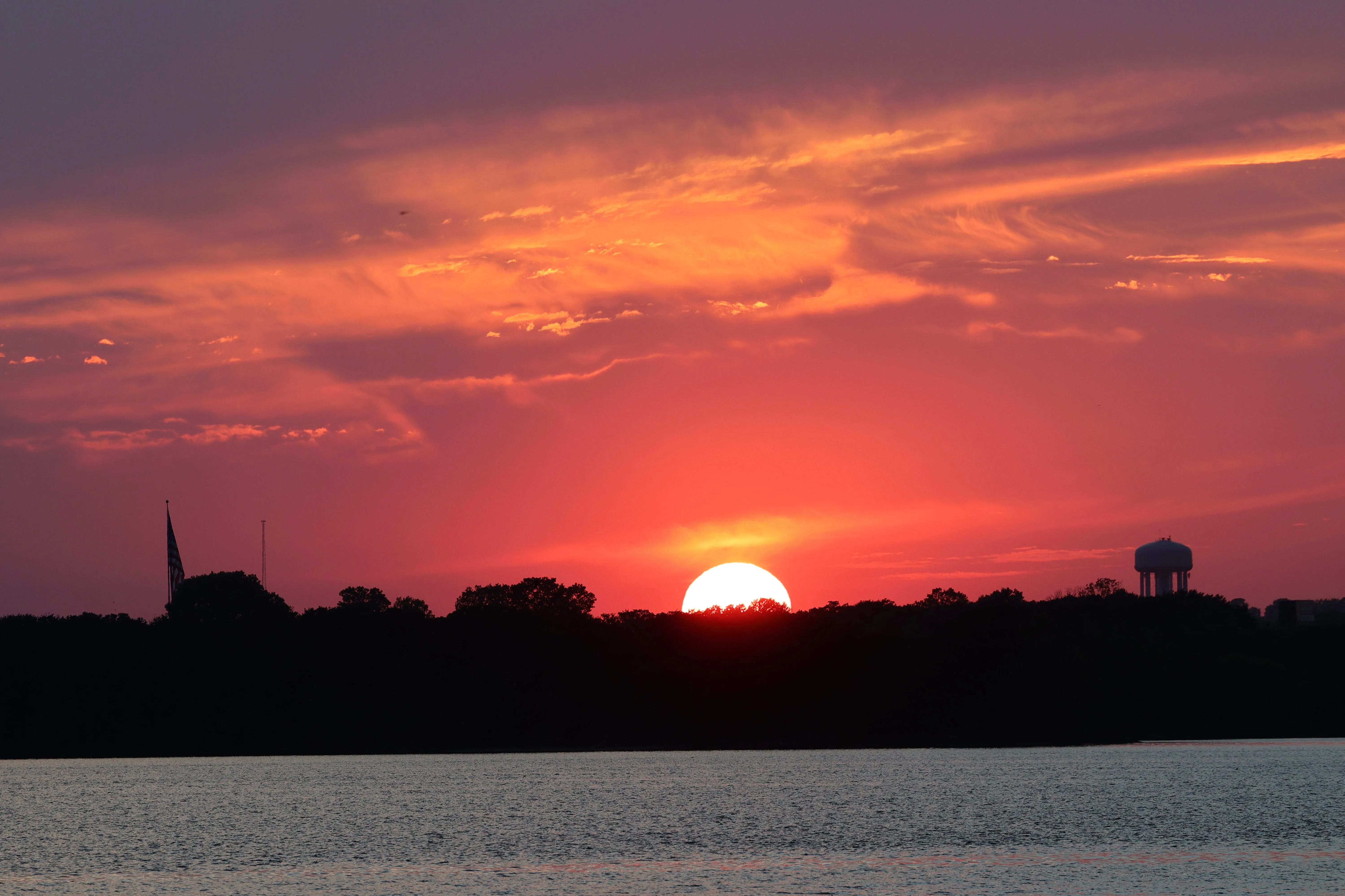 Pink and purple sunset with church spire and water tower silhouette